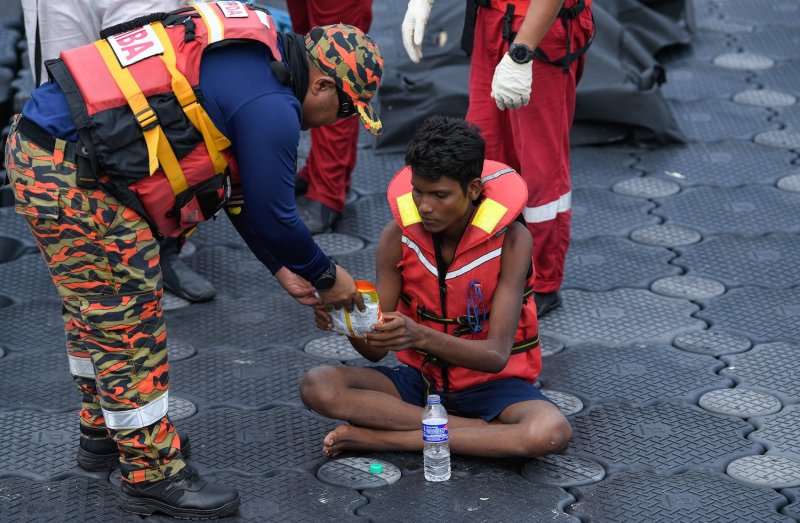 A Malaysian rescuer provides food to Rohingya migrant Iman Sharif, days after his boat carrying migrants from Myanmar capsized near the Malaysia–Thailand border, at a jetty in Langkawi on Nov 11, 2025. (Photo: Reuters)