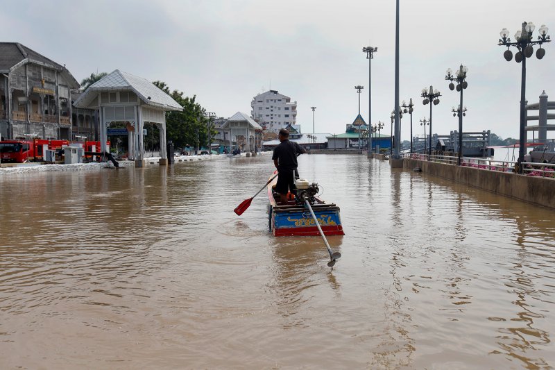 A man navigates his boat through a flooded area at the Clock Tower pier in Nonthaburi. (Photo: Pattarapong Chatpattarasil)
