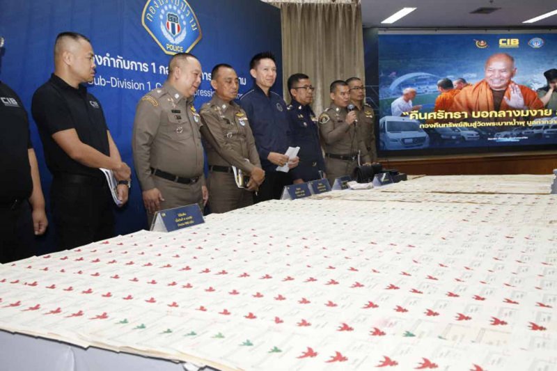 Senior police officers display dozens of land title deeds retrieved for Wat Phrabat Namphu at the Crime Suppression Division in Bangkok on Thursday. A picture of the temple’s former abbot was displayed on the backdrop. (Photo: Pattarapong Chatpattarasill)