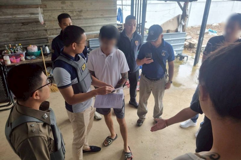 A Thai police officer shows a warrant to Eng Sie, one of 34 suspects wanted by Singapore police in connection with a Cambodia-based scam operation, at a house in Khon Kaen. (Photo: supplied/Chakkrapan Natanri)