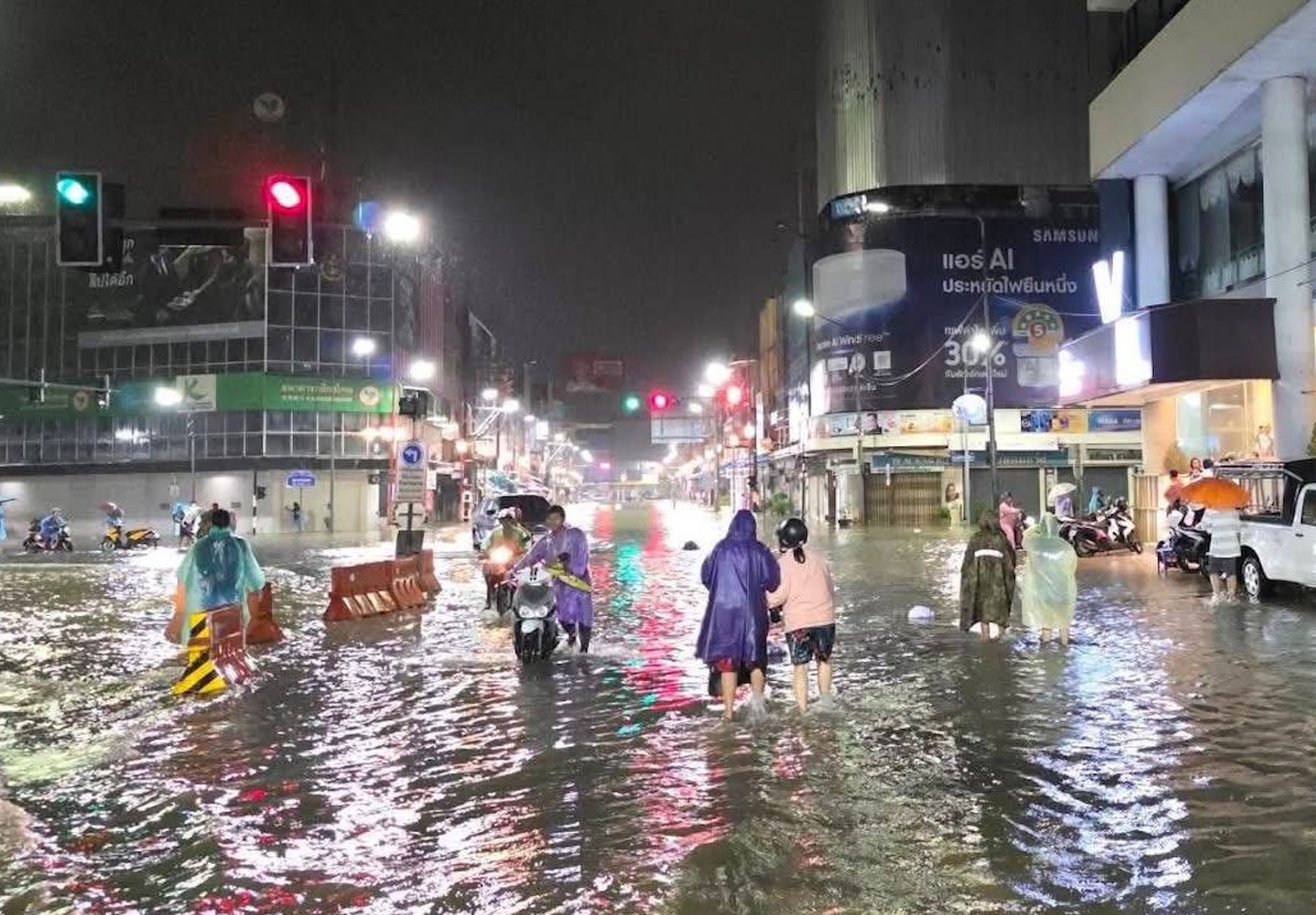 Pedestrians navigate a flooded street in Hat Yai on Friday night. The city’s mayor on Saturday declared a “red flag” alert after 595mm of rain fell. (Photo: Phusadee Muhamad)