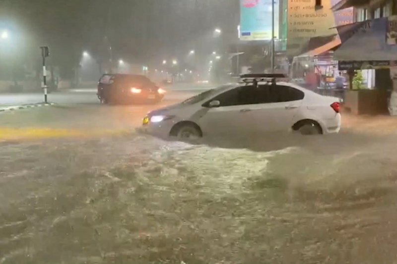Vehicles struggle through rising waters on a road in Hat Yai district of Songkhla province, amid overnight rain on Friday. (Photo via Assawin Pakkawan)