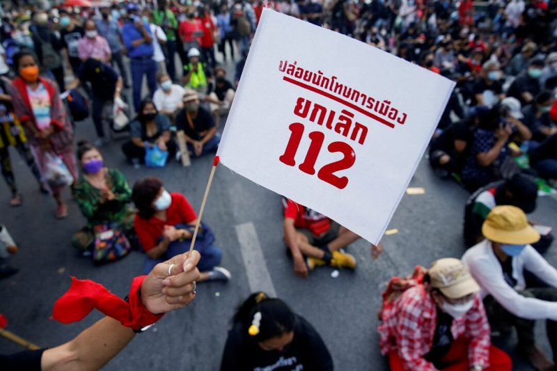 A person holds a flag reading “Release political prisoners, cancel 112” during a protest against the lese majeste law, in Bangkok on Dec 12, 2021. (Photo: Reuters)