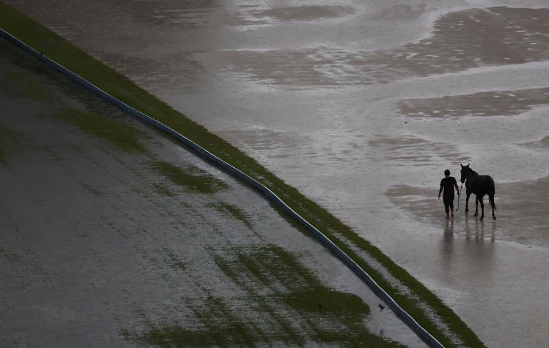 A man walks a horse as rain pours in Kuala Lumpur on Monday. (Photo: Reuters)