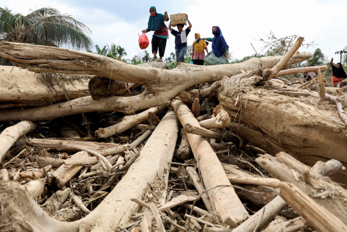 Indonesians climb over logs to get to flood aid centre