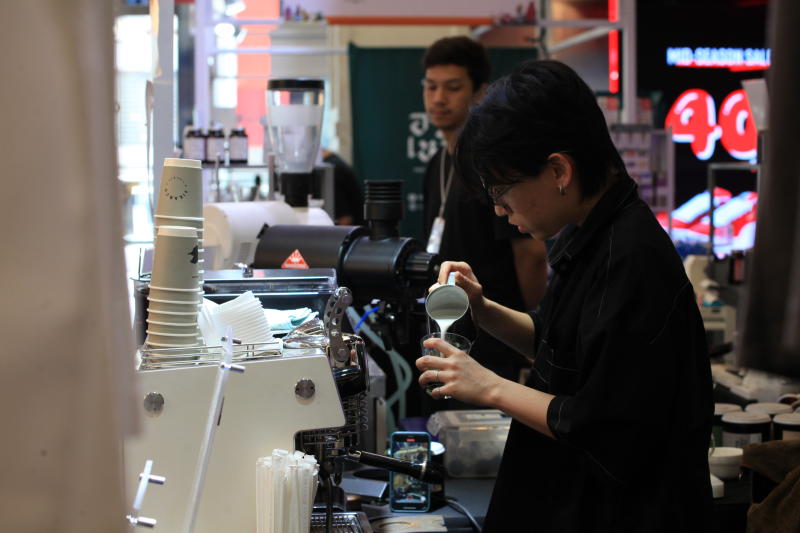 A barista pours steamed milk into coffee at a shopping centre in Bangkok. (Photo: Apichart Jinakul)