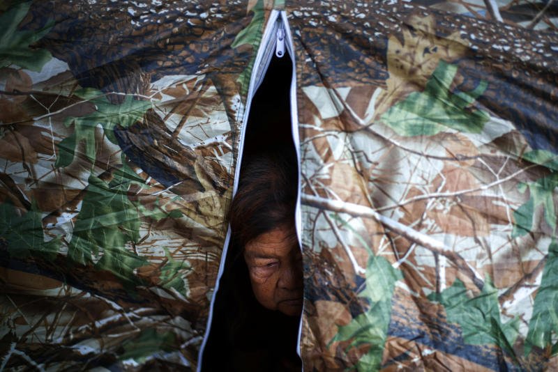 A woman looks out from inside her tent at a temporary shelter amid deadly clashes between Thailand and Cambodia along a disputed border area, in Surin province, on Dec 11, 2025. (Photo: Reuters)