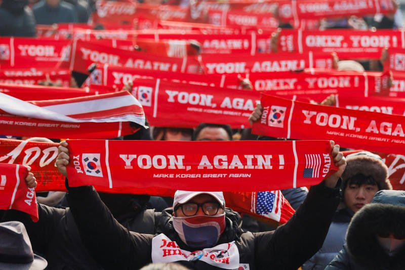 A group of far-right protesters gathering to support Yoon Suk Yeol hold banners with a slogan, before a bus carrying the former South Korean president arrives at the Seoul Central District Court in Seoul on Friday. (Photo: Reuters)