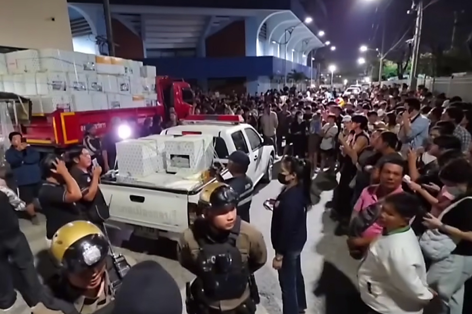 A large crowd gathers on Monday night outside the Muang Chon Buri district office, opposite a gymnasium where ballot boxes were being stored, demanding an investigation into several suspicious developments in the vote counting in Constituency 1.