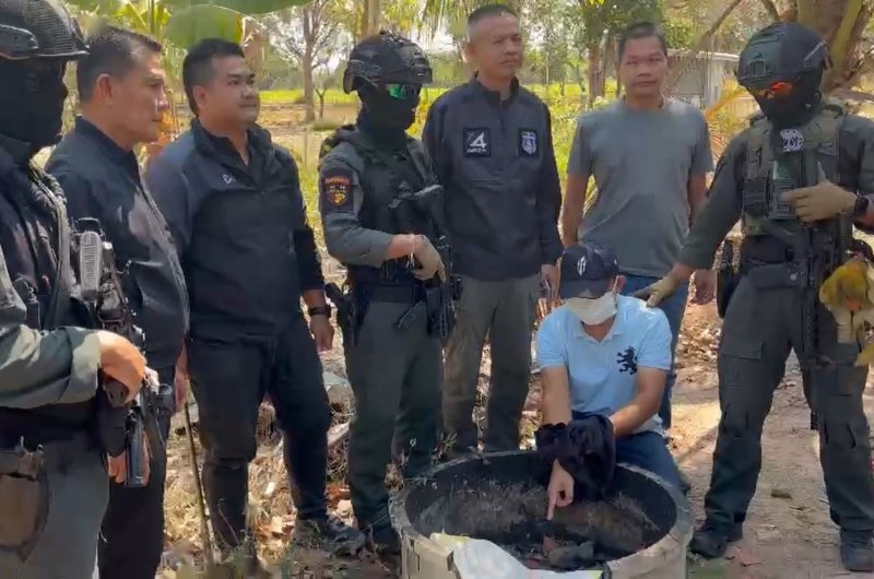 A suspect, 48, seated, wanted for the gold shop robbery in Khon Kaen last Sunday, points at an area where some stolen gold ornaments were hidden following his arrest on Saturday. (Photo: Chakkrapan Natanri)