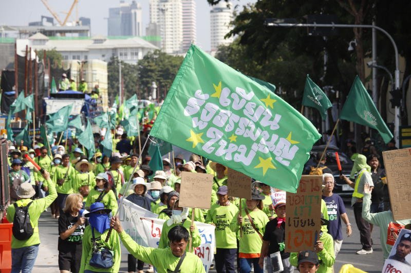 Supporters move along Bangkok streets with green flags reading "Writing a new constitution" during a walking campaign on Dec 10, 2025. (Photo: Pattarapong Chatpattarasill)