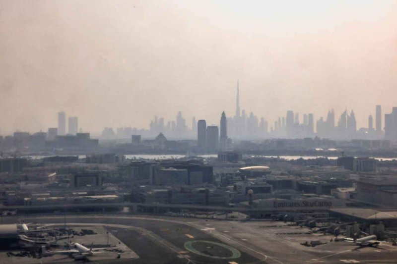 A view from inside a stained window of an airplane shows Dubai International Airport, with the Burj Khalifa in the background, amid the U.S.-Israeli conflict with Iran, in Dubai, United Arab Emirates, March 8, 2026. REUTERS