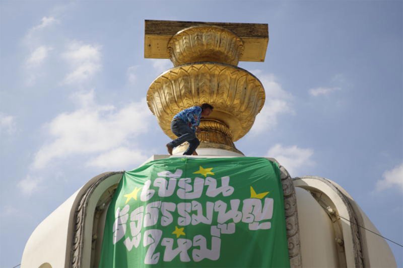 A political activist puts up a green banner at the Democracy Monument on Dec 10, 2025, calling on voters to support a rewrite of the nation's charter. (Photo: Pattarapong Chatpattarasill)