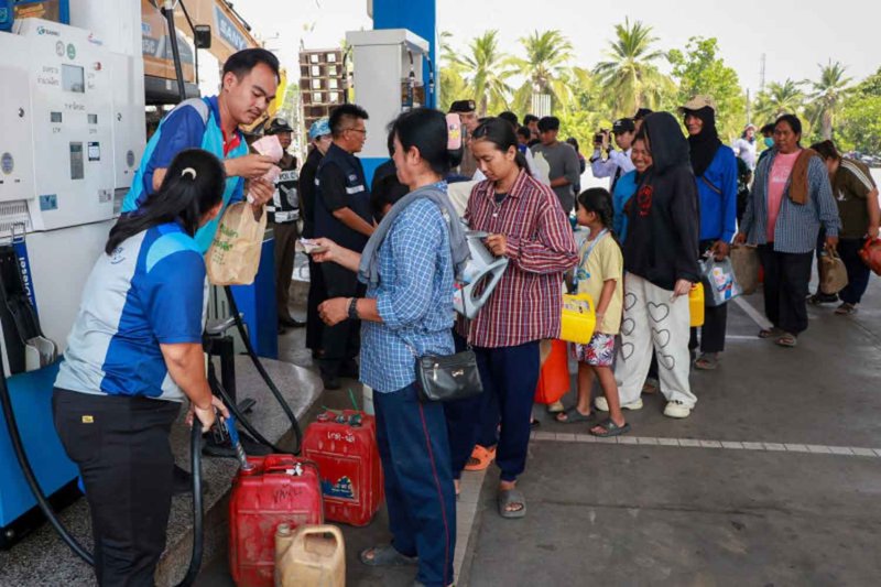 People with containers queue at a PTT petrol station in Sawankhalok district of Sukhothai to purchase diesel, as the station introduces a 250-card daily rationing system for the first time on Tuesday. (Photo: Sukhothai Public Relations Office)