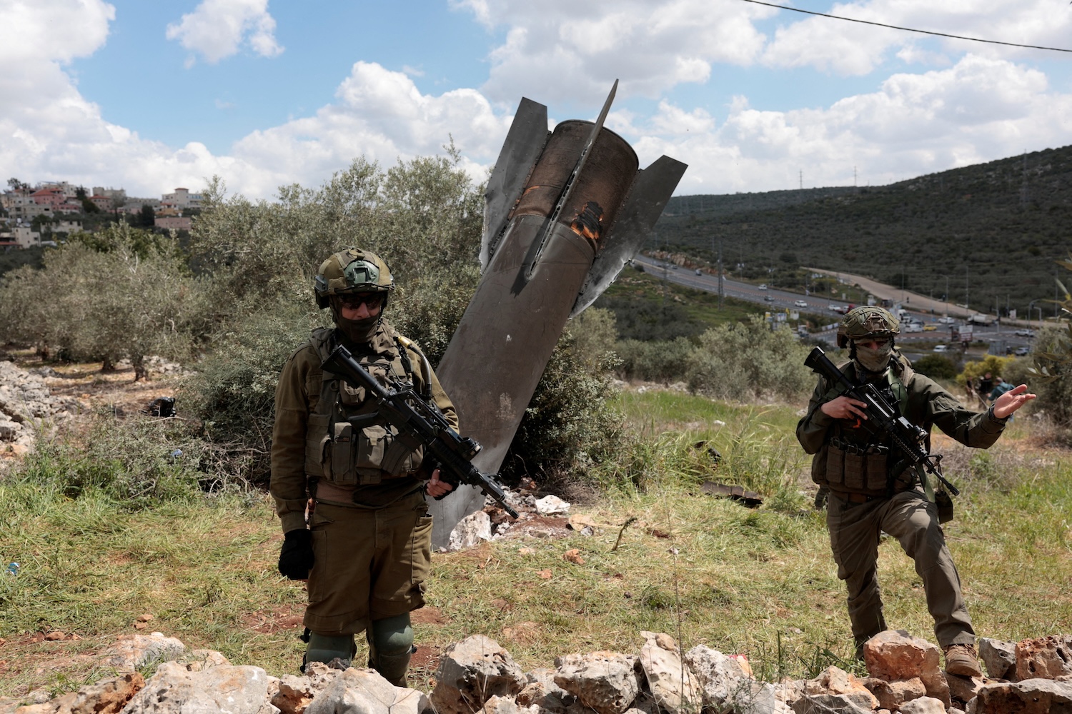 Israeli soldiers stand guard near remnants of a missile stuck in the ground in a village near Nablus in the Israeli-occupied West Bank, on March 24, 2026. (Photo: Reuters)