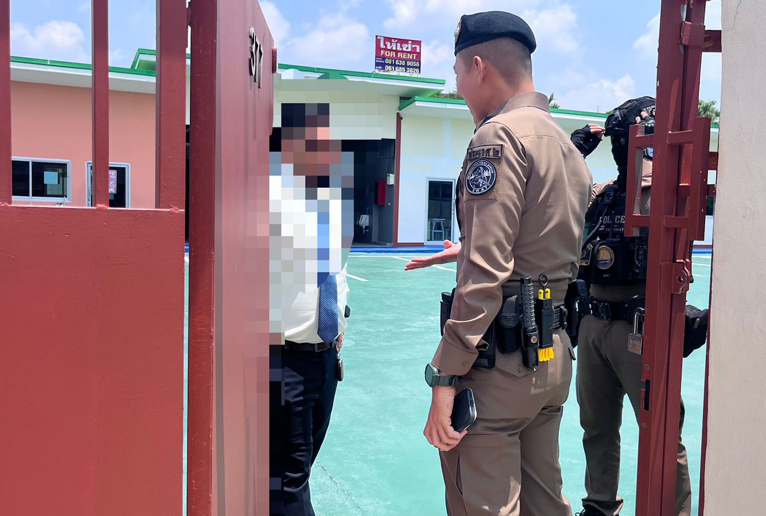 Police talk to a staff member of an international school in Bangkok's Prawet district, which was found to be operating without a licence and employed 10 foreign nationals who had no work permits. (Photo: Prawet police station) 