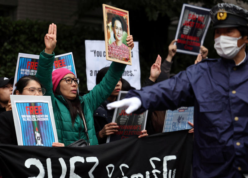 A Myanmar protester residing in Japan shows off the portrait of Aung San Suu Kyi and raises three-finger salute while a Japanese police officer gestures near them during a rally denouncing an upcoming election led by the military junta and demanding the immediate release of Myanmar's detained former leader Aung San Suu Kyi and all political prisoners, outside Myanmar's embassy in Tokyo, Japan, on Dec 14, 2025. (Photo: Reuters)