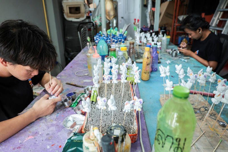 A staff member paints art toys by hand for Gashapon toy capsules, amid rising plastic prices linked to the US-Israel-Iran conflict, at MOTMO Studio, in Bangkok. (Photo: Reuters)