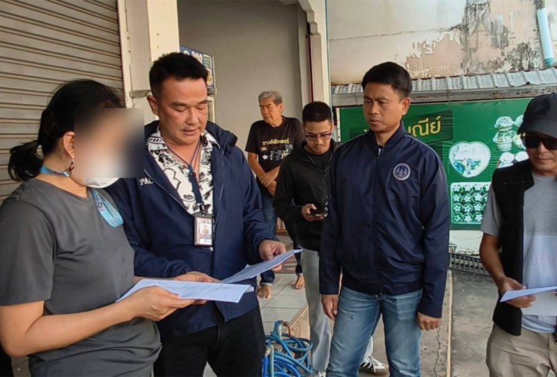 A former finance and accounts officer at Udonthani Cancer Hospital is served with an arrest warrant outside the shop where she had a fried pork stall in Muang district of Uttaradit province on Monday. The 48-year-old woman is accused of embezzling more than 23 million baht from the hospital before fleeing to evade arrest. (Photo: Public Sector Anti-Corruption Commission)