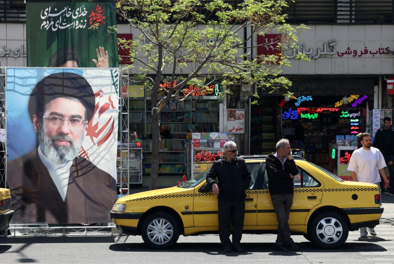 A taxi stands next to a banner depicting Iran's new supreme leader Ayatollah Mojtaba Khamenei, along a street in Tehran. (Photo: AFP)