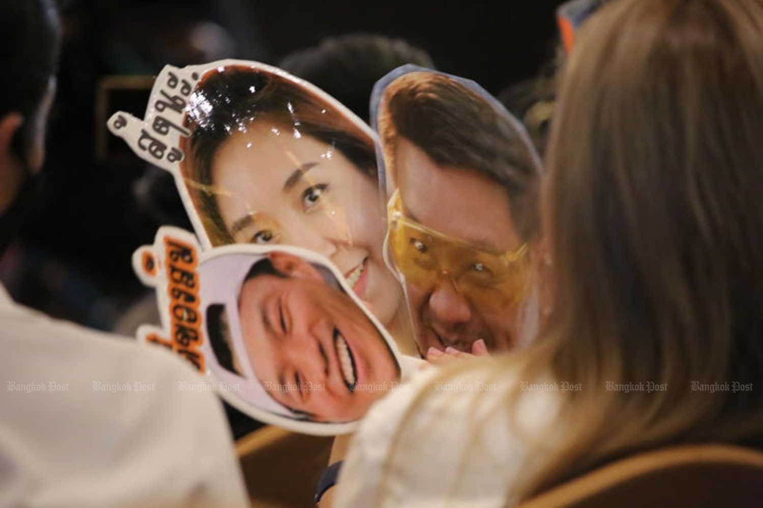 Supporters hold placards bearing images of People&rsquo;s Party leader Natthaphong Ruengpanyawut and deputy leaders Sirikanya Tansakun and Veerayooth Kanchoochat, to show encouragement during a party press conference at the Maple Hotel in Bang Na district of Bangkok on Friday. (Photo: Somchai Poomlard)  