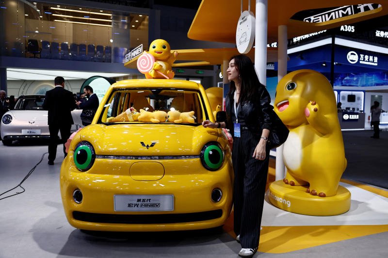 A woman poses next to the fifth generation Wuling Hongguang MiniEV electric vehicle displayed at the Beijing International Automotive Exhibition, or Auto China, in Beijing, on Friday. (Photo: Reuters)