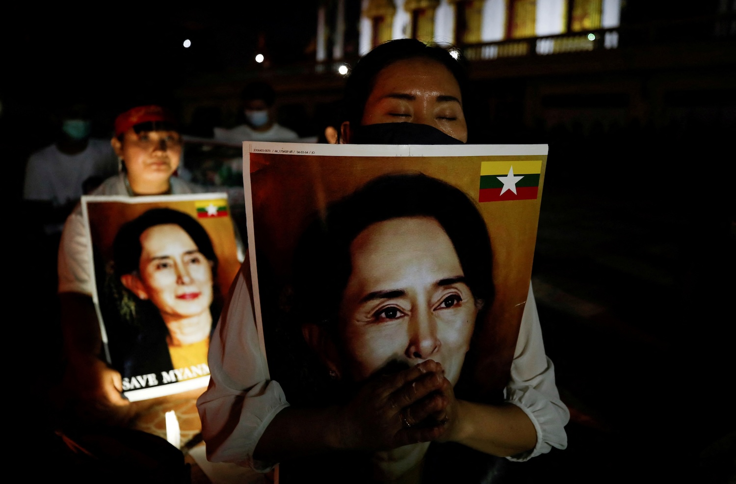 Migrant workers protesting against the military junta in Myanmar hold pictures of Aung San Suu Kyi, during a candlelight vigil at a temple in Bangkok, on &nbsp;March 28, 2021. (Photo: Reuters)