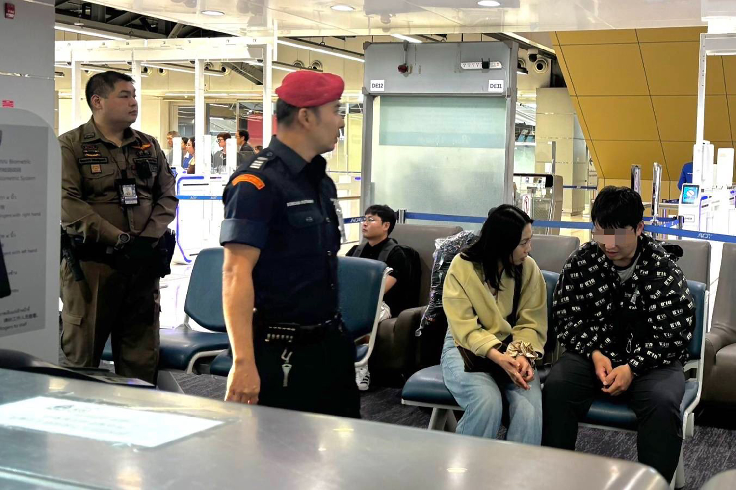 A Chinese man, right, listens to his wife after the incident at Suvarnabhumi airport on Wednesday as airport security officers look on. (Photo: Immigration Bureau)