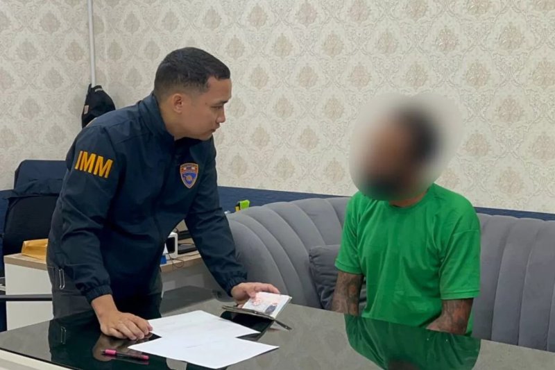 A Phuket immigration officer questions an Austrian man identified only as Raphael after his arrest for causing a disturbance on Tuesday. (Photo: Achadthaya Cheunniran)