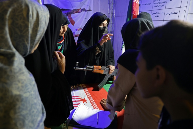 An Iranian military personnel, centre, educates women about how to use a gun at a booth in Hafte Tir Square, in Tehran on May 17.