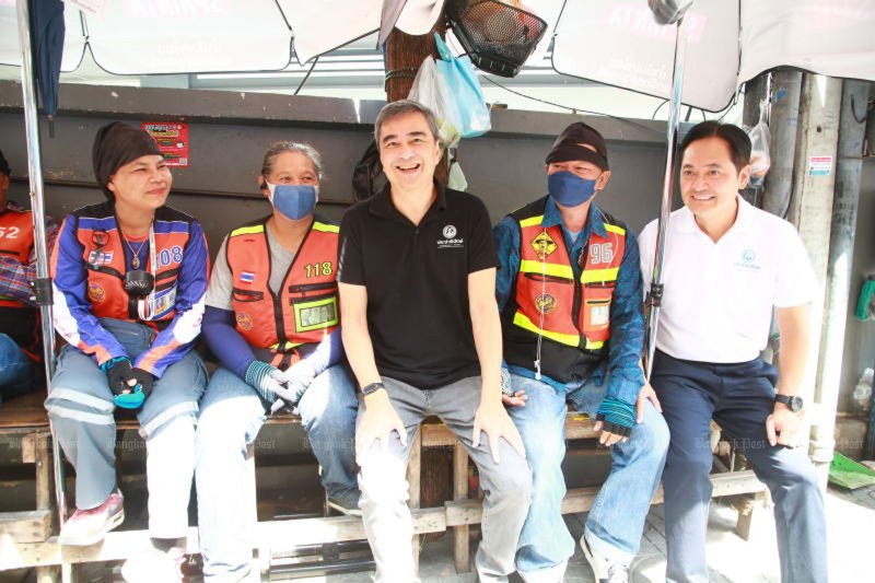 Abhisit Vejjajiva, leader of the opposition Democrat Party, centre, and Anucha Burapachaisri, the party's Bangkok governor candidate, right, sit with motorcycle taxi riders during a field inspection in Sukhumvit Soi 4 on Saturday. (Photo: Somchai Poomlard)