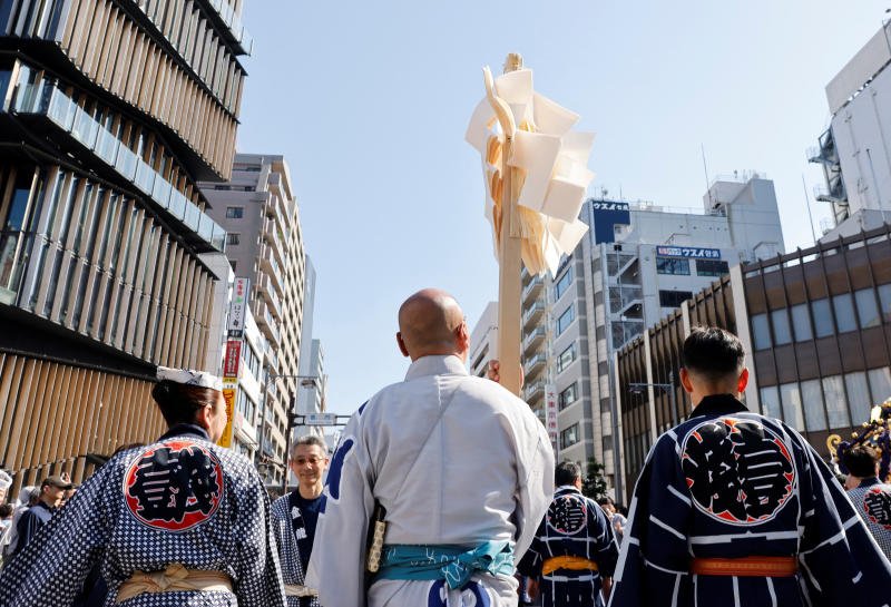 An attendant watches people carrying a Mikoshi, a portable shrine, in front of the Senso-ji Temple during the Sanja Matsuri or Sanja Festival, one of the three largest Shinto festivals in Tokyo, at Asakusa district in Tokyo on May 17, 2026. (Photo: Reuters)