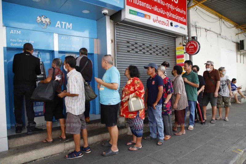 People gather outside Krungthai Bank’s Bang Yai Market branch in Nonthaburi on June 4 seeking help in registering for the new round of state welfare cards. Pattarapong Chatpattarasill