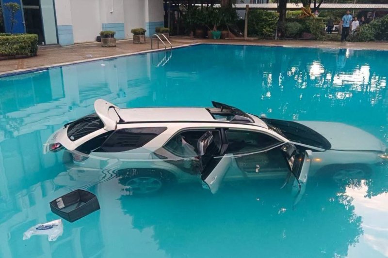 A car lies in a pool at Chulalongkorn University after the driver accelerated through a barrier fence despite attempts by security staff to stop him. (Photo: บิ๊กเกรียน, Nok สื่อสาร34 ธน5808)