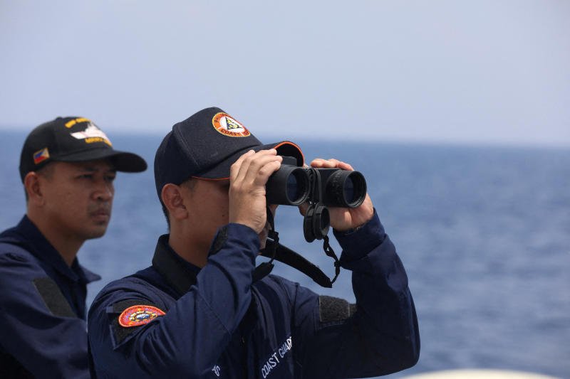 A Philippine Coast Guard personnel looks through a binocular while conducting a resupply mission for Filipino troops stationed at a grounded warship in the South China Sea, on Oct 4, 2023. (File photo: Reuters)