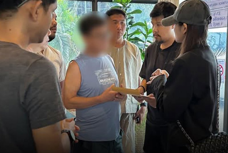 Immigration officers question a South Korean man named in an Interpol red notice as a suspect in online gambling and scam operations in his home country, at a health massage shop in Pattaya on Friday. (Photo: Police TV)