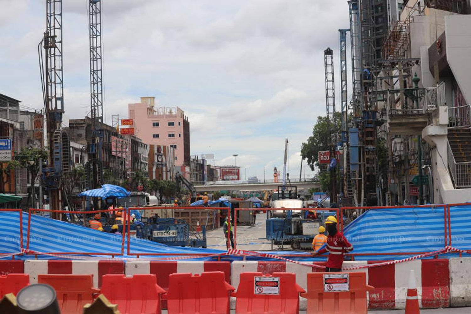 Workers stand beside the site of a removed pedestrian bridge near Wongwian Yai intersection on July 12, where the MRTA is carrying out repairs to stop water leaking into the Purple Line tunnel.  (Photo: Apichart Jinakul)