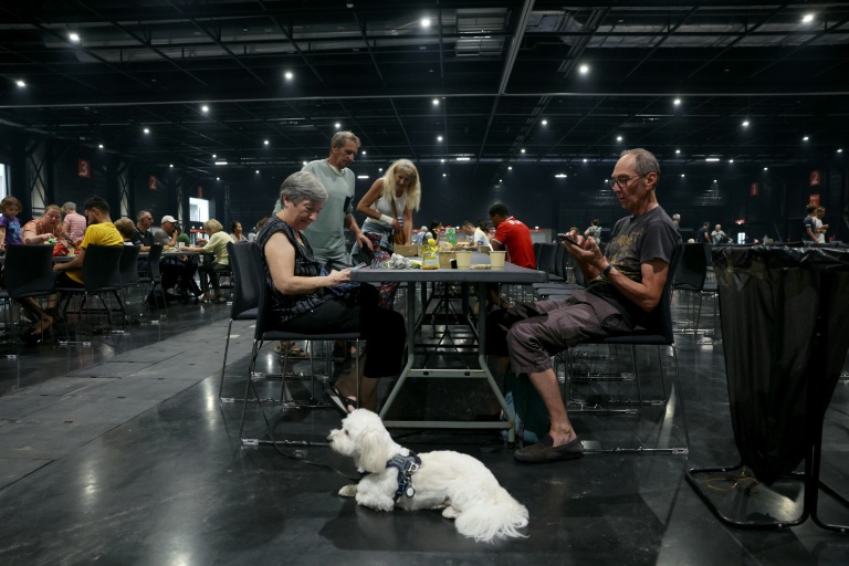 People evacuated due to wildfires have a meal as they shelter at the Parc des Expositions de Bordeaux on July 25, 2026. France and Spain have evacuated more than 160,000 people as unprecedented forest fires ravaged areas near Madrid and Bordeaux. (Photo: AFP)