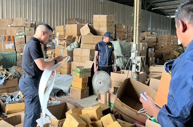 Cảnh sát kiểm tra các sản phẩm giả nhãn hiệu được tìm thấy trong một cuộc đột kích vào kho hàng ở quận Min Buri, Bangkok hôm thứ Ba. (Ảnh: Cục Điều tra Trung ương)
