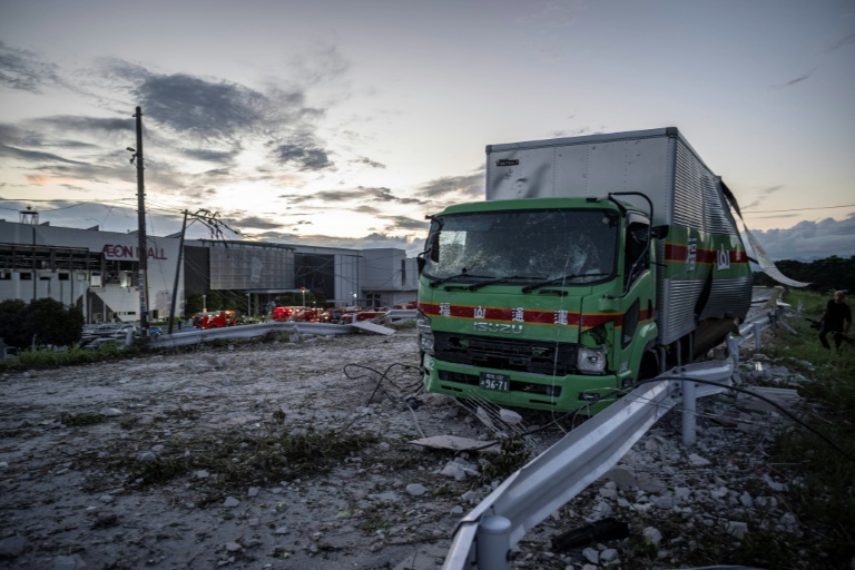 A damaged truck is seen on a debris-covered road in Kashima, Kumamoto Prefecture