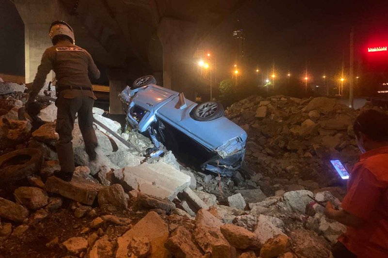 A policeman approach the pickup truck after it fell from the elevated expressway in Ratchathewi district, Bangkok, early Sunday morning. Police photos