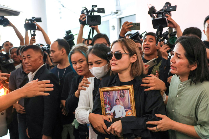 A group of people gathered indoors, with one woman holding a framed picture.