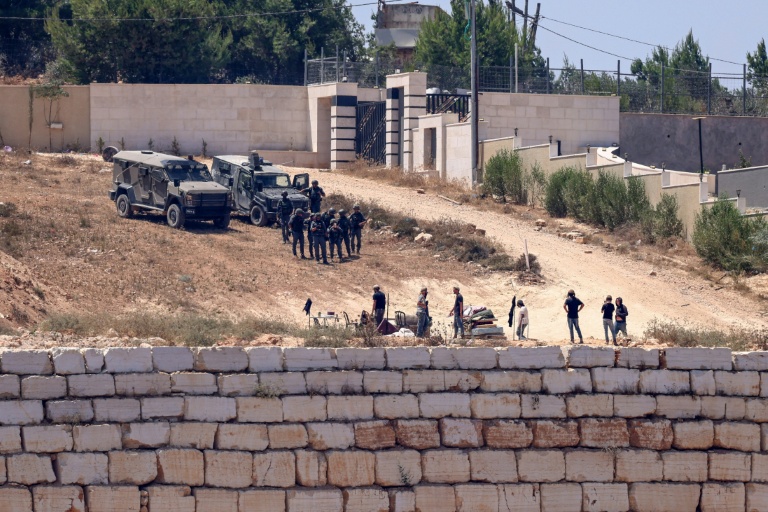 Israeli soldiers stand guard next to settlers in front of Palestinian houses in the village of Qusra, south of Nablus, in the occupied West Bank. (Photo: AFP)