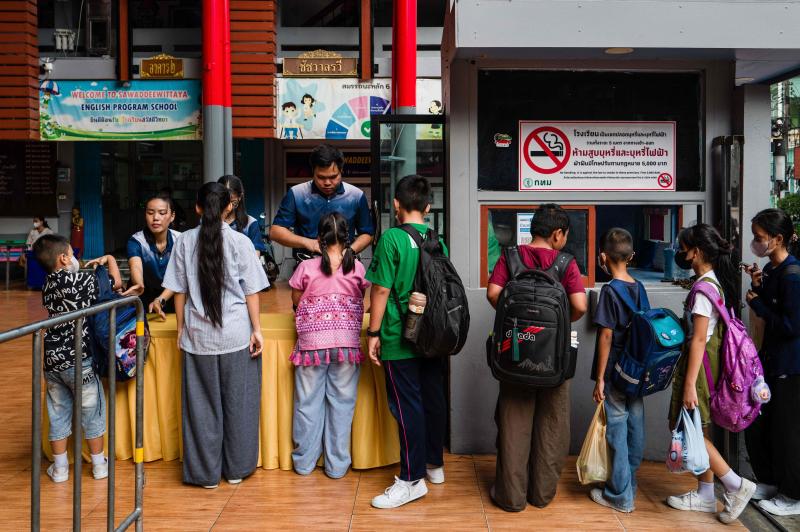 Staff inspect backpacks due to new security measures as students arrive at Sawasdee Wittaya School in Bangkok on Friday. Dozens of students queued at a Bangkok school, handling backpacks to teachers for security checks, a week after a deadly shooting in one of&nbsp;Thailand's worst attacks in recent years. The cabinet this week declared school safety a national priority, ordering schools nationwide to screen for weapons and step up security. (Photo: AFP)