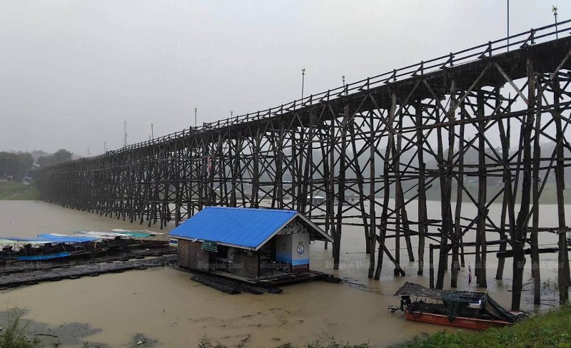 Visitors and residents are warned to exercise caution near the 850-metre-long Uttamanusorn Bridge, better known as Saphan Mon, in Kanchanaburi's Sangkhla Buri district as continuous heavy rain has caused water levels in the Song Kalia River to rise rapidly. Strong currents and floating debris have been reported near the country's longest wooden bridge. (Photo: Piyarach Chongcharoen)