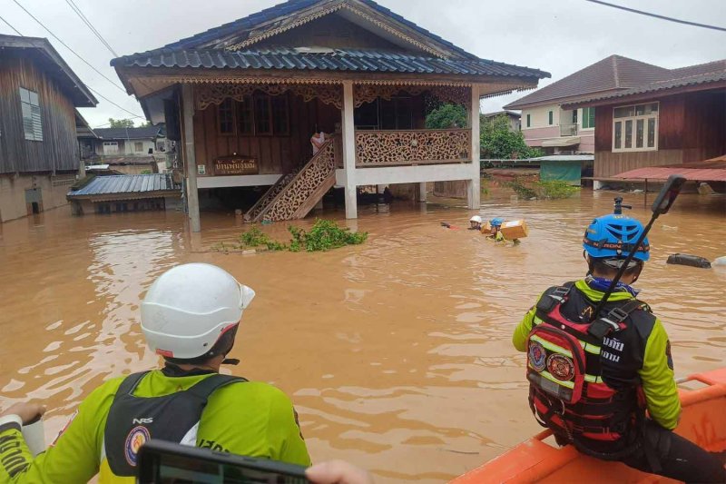 Rescuers distribute food to residents of a flooded riverside community beside the Nan River in Muang district of Nan province on Thursday morning. (Photo: Nan Public Relations Department)