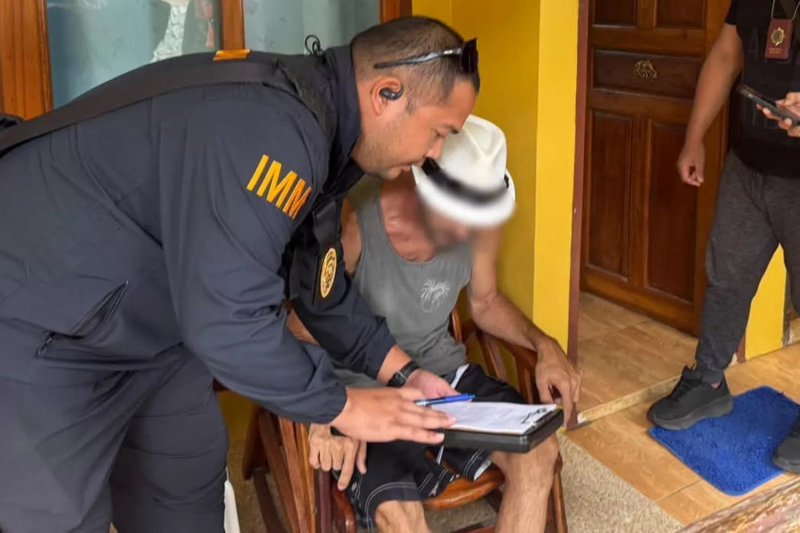 A police officer questions Lance Beck. (Photo: Phuket Immigration Office)