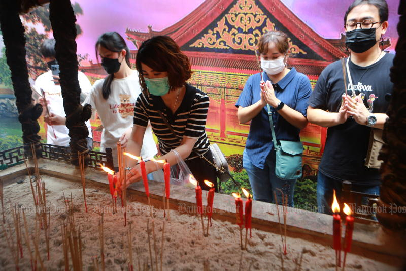 People make merit with incense and candles at a Buddhist temple in Bangkok. (Photo: Somchai Poomlard)