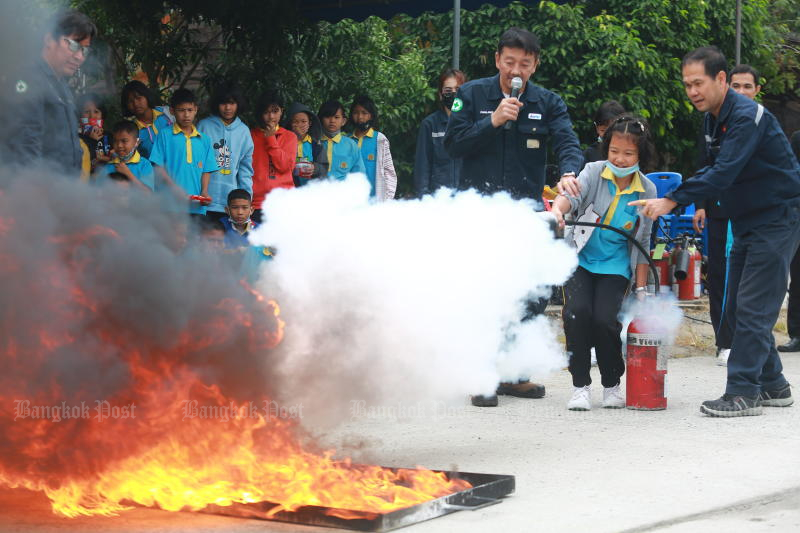 Fire volunteers teach a student use fire extinguisher at a school in Samut Prakan province. (Photo: Somchai Poomlard)