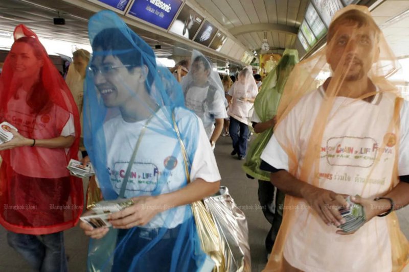Volunteers cover themselves with mock-up condoms to attract passers-by as they distribute leaflets about HIV/Aids protection at a skytrain station in Bangkok. (File photo)